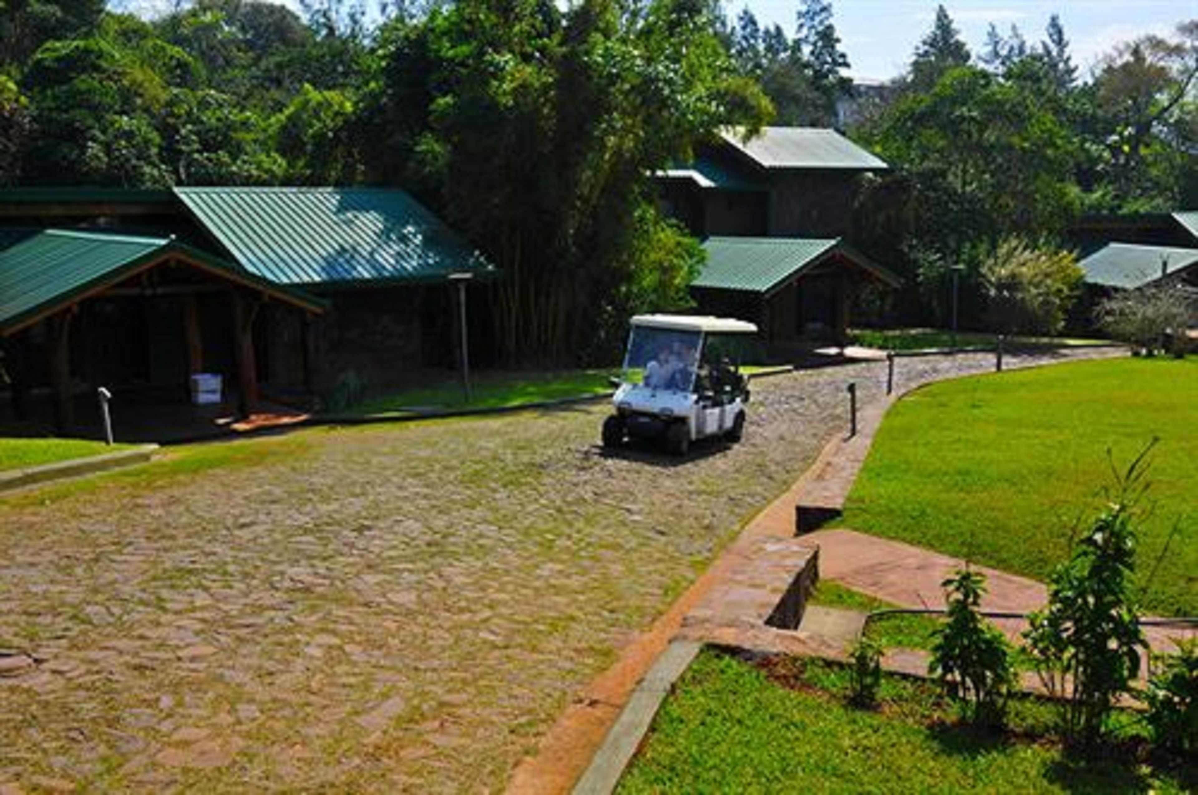 A lodge with multiple green-roofed cabins, a paved driveway, and a grassy area.