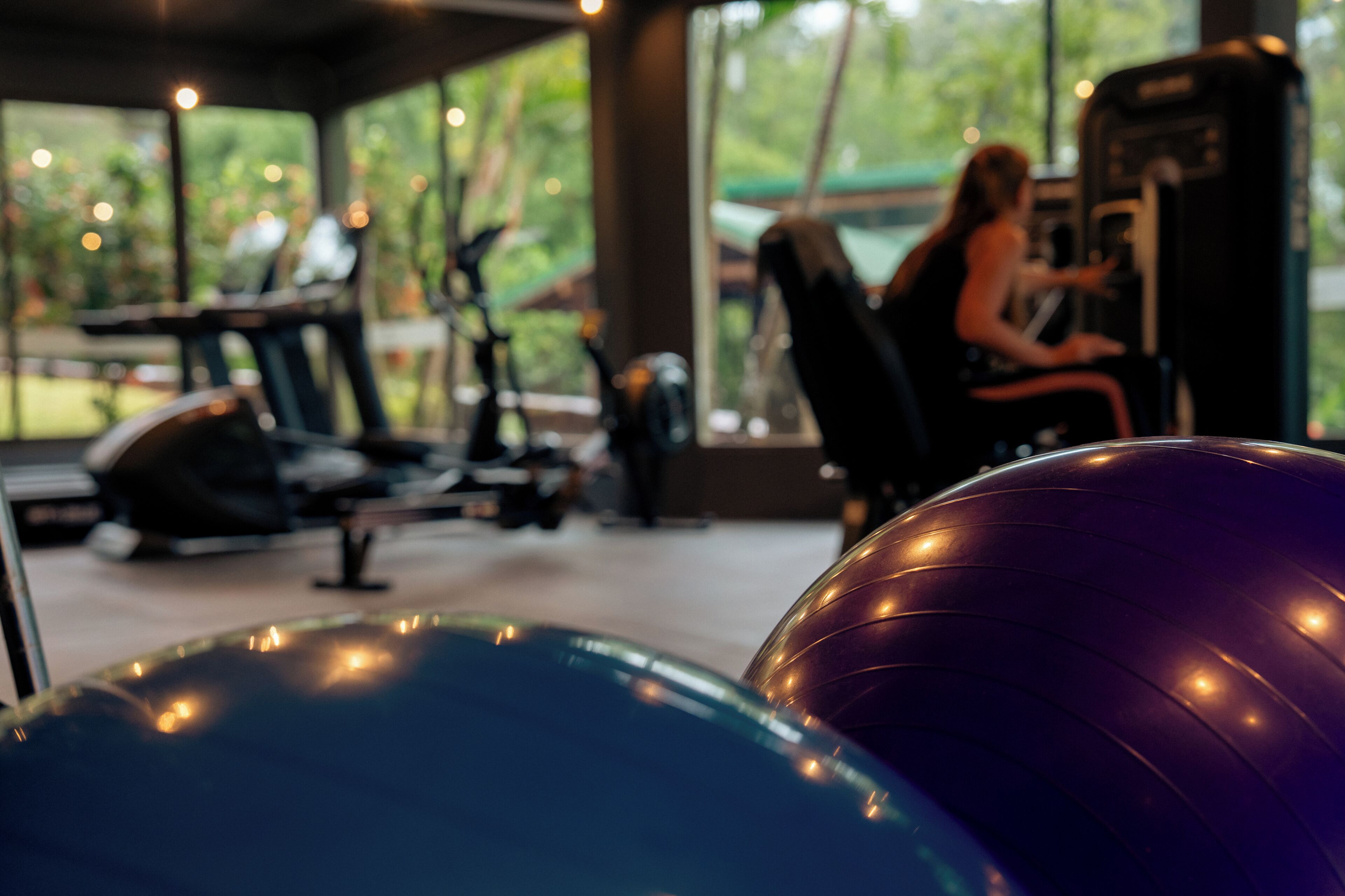 A gym with exercise equipment and a person using a machine.