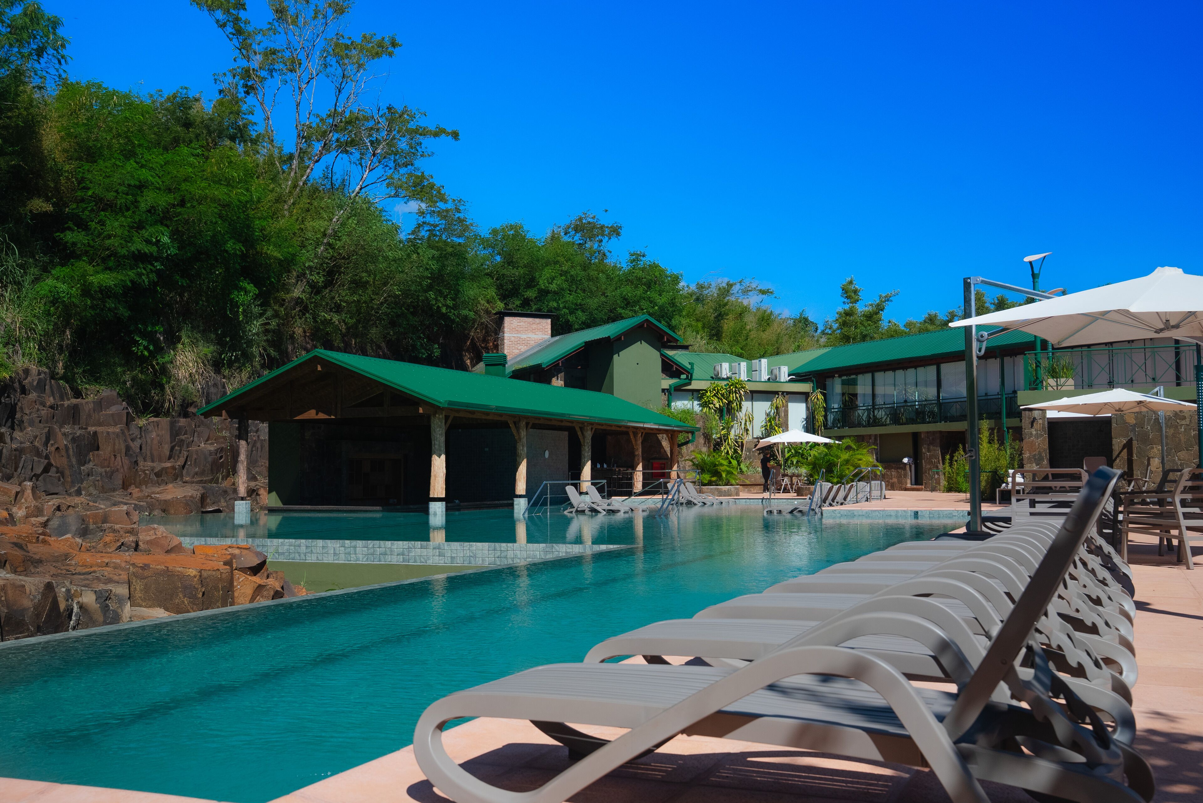 A pool area with lounge chairs and a building with a green roof.