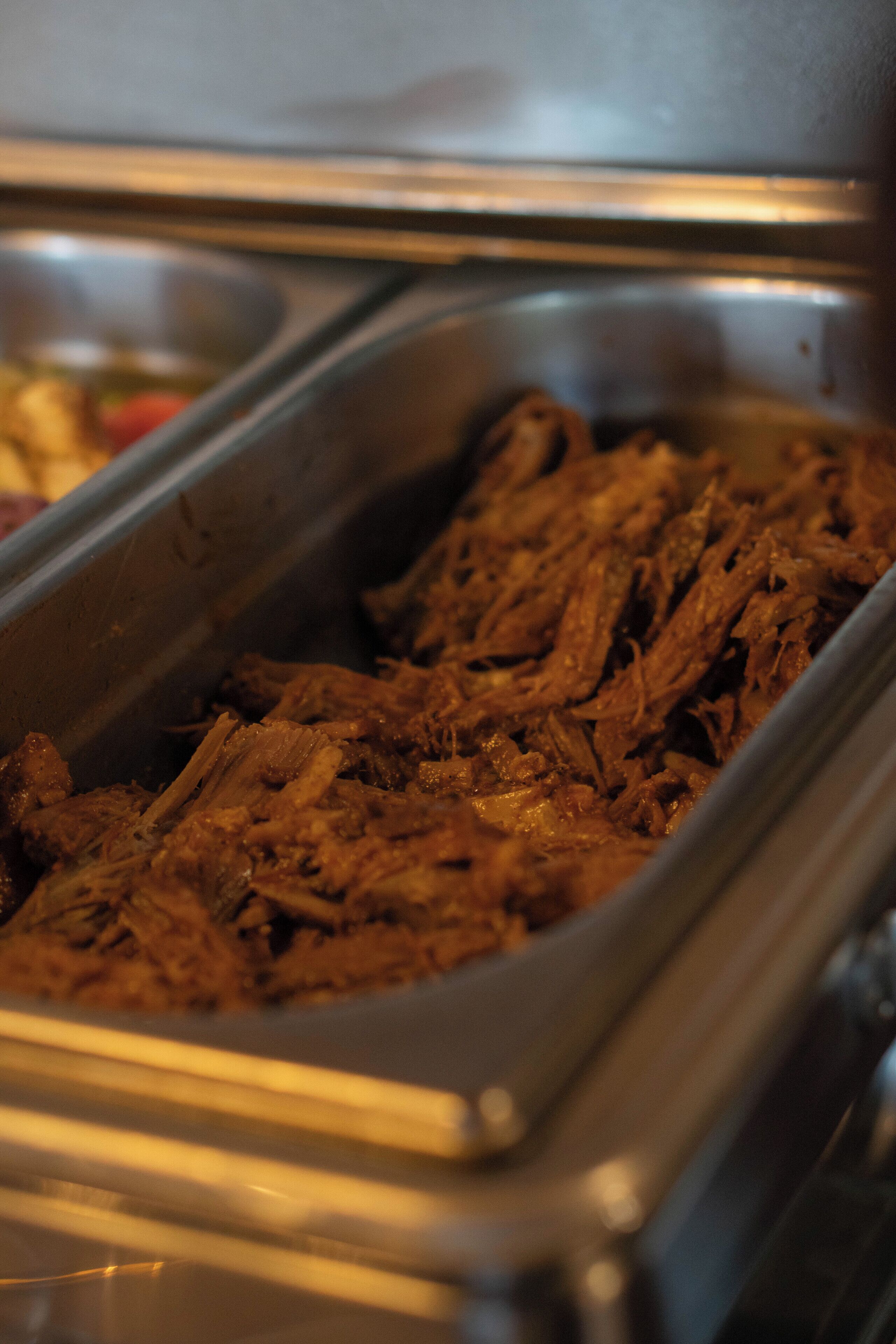 Een buffet met diverse gerechten, waaronder een grote bak met geraspt vlees.