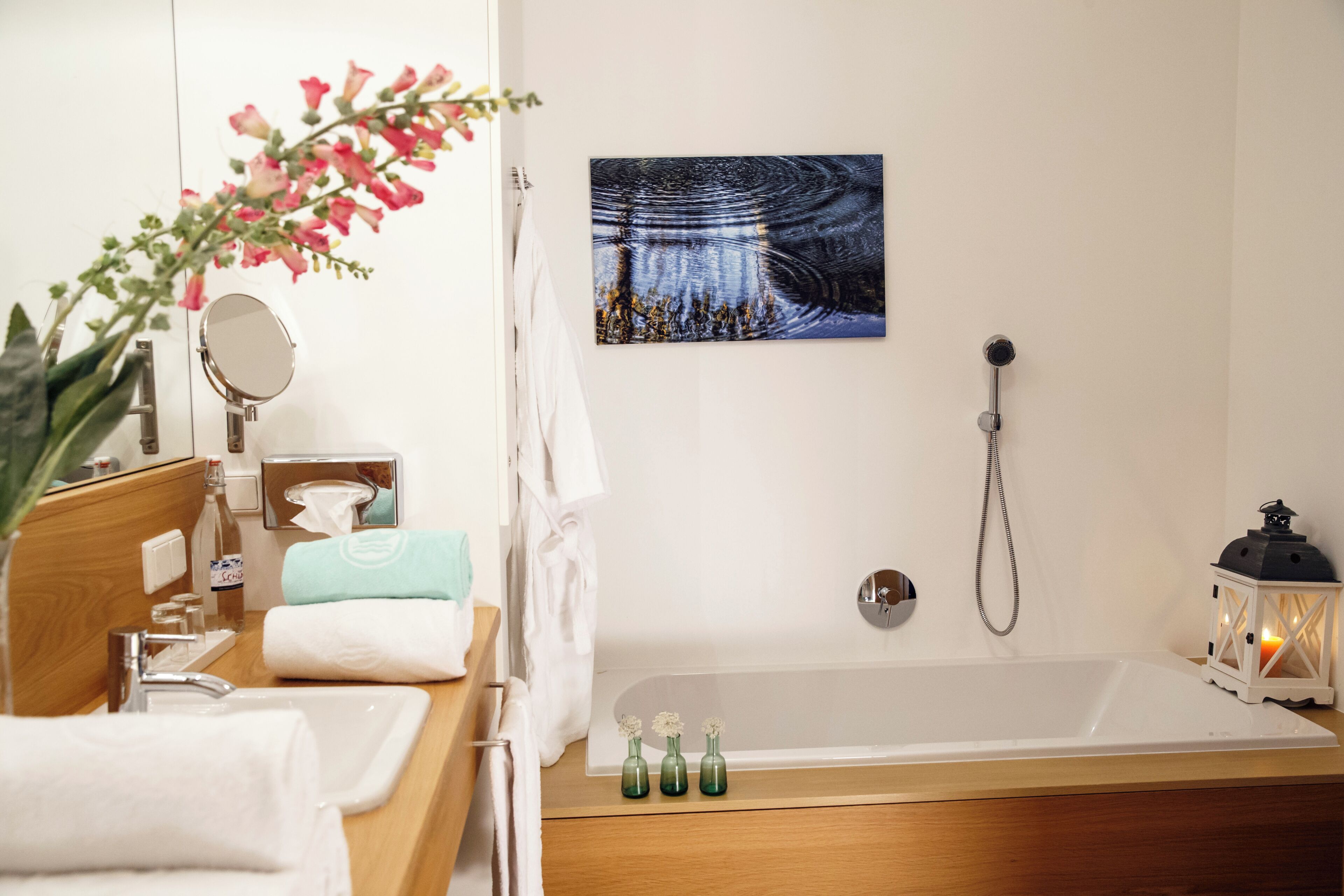 Ein Badezimmer mit einer Badewanne, einem Spiegel, einem Waschbecken und einem Wandbild.
