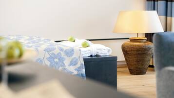 Una habitación de hotel con una cama, una lámpara, una silla y una pequeña mesa con manzanas.