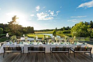 A deck with a table set for a meal, overlooking a lake and golf course.