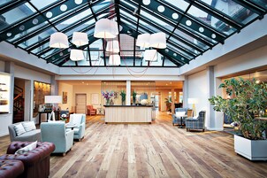 A spacious lobby with a high ceiling, a reception desk, and seating areas.