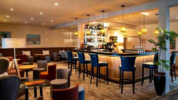 A bar area with a counter, stools, and a variety of bottles.