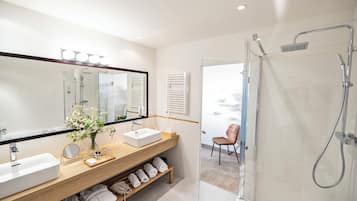 Un baño moderno con un espejo grande, dos lavamanos, una ducha y un mueble de tocador de madera.