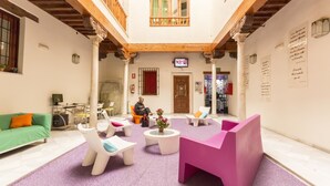 A spacious indoor area with a high ceiling, wooden beams, and a central seating area with modern furniture. - White Nest (Granada)