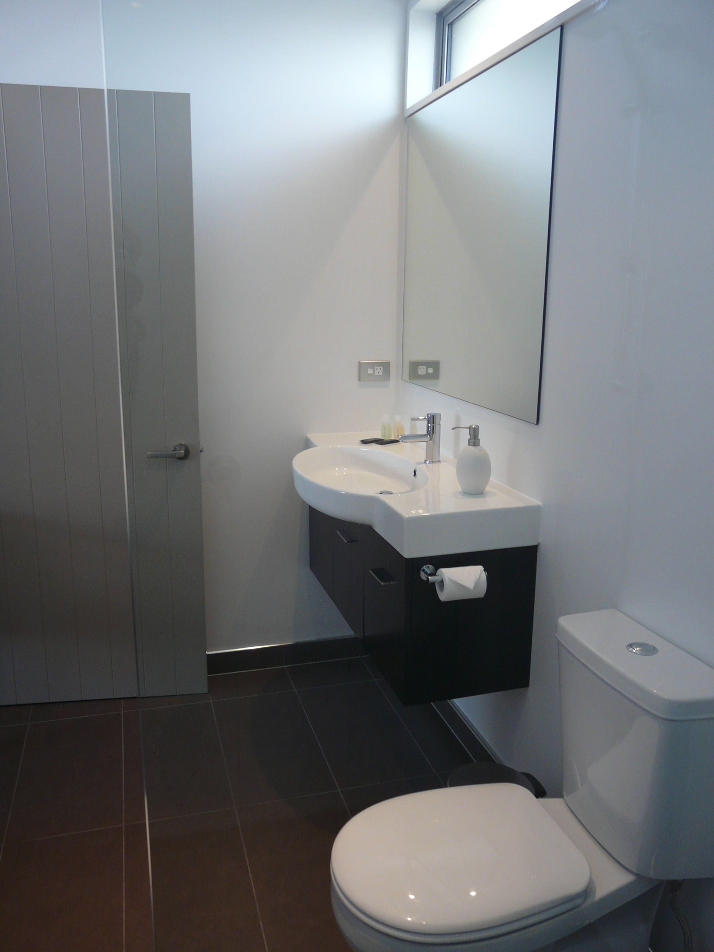A modern bathroom with a toilet, sink, and mirror.