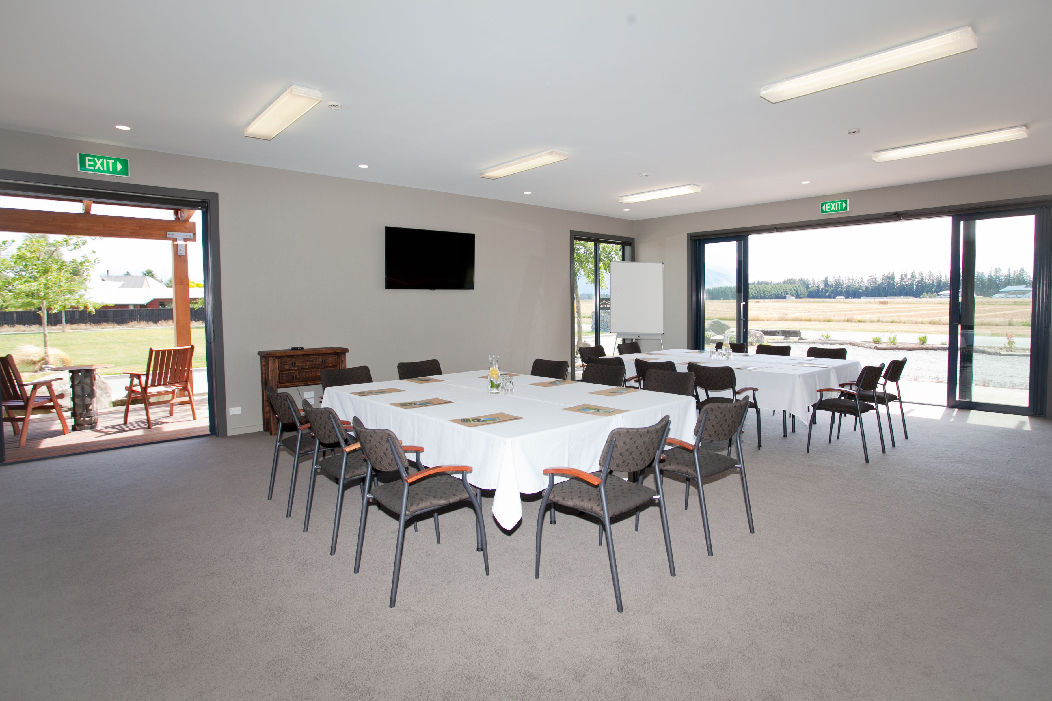 Un salón de conferencias con una gran mesa, sillas y una pizarra. Hay ventanas con vistas al exterior.