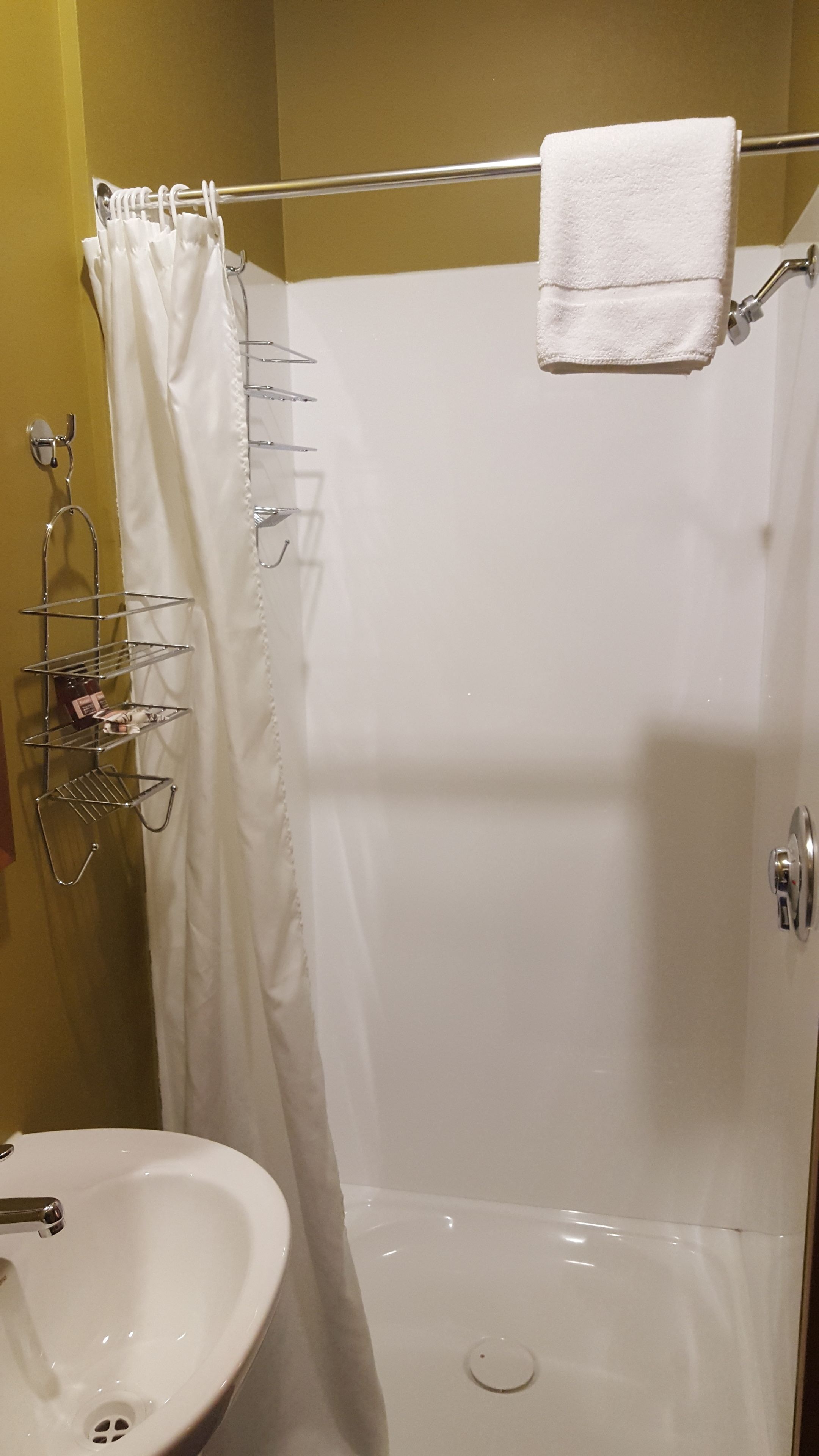 A bathroom with a shower, a white sink, and a towel rack.