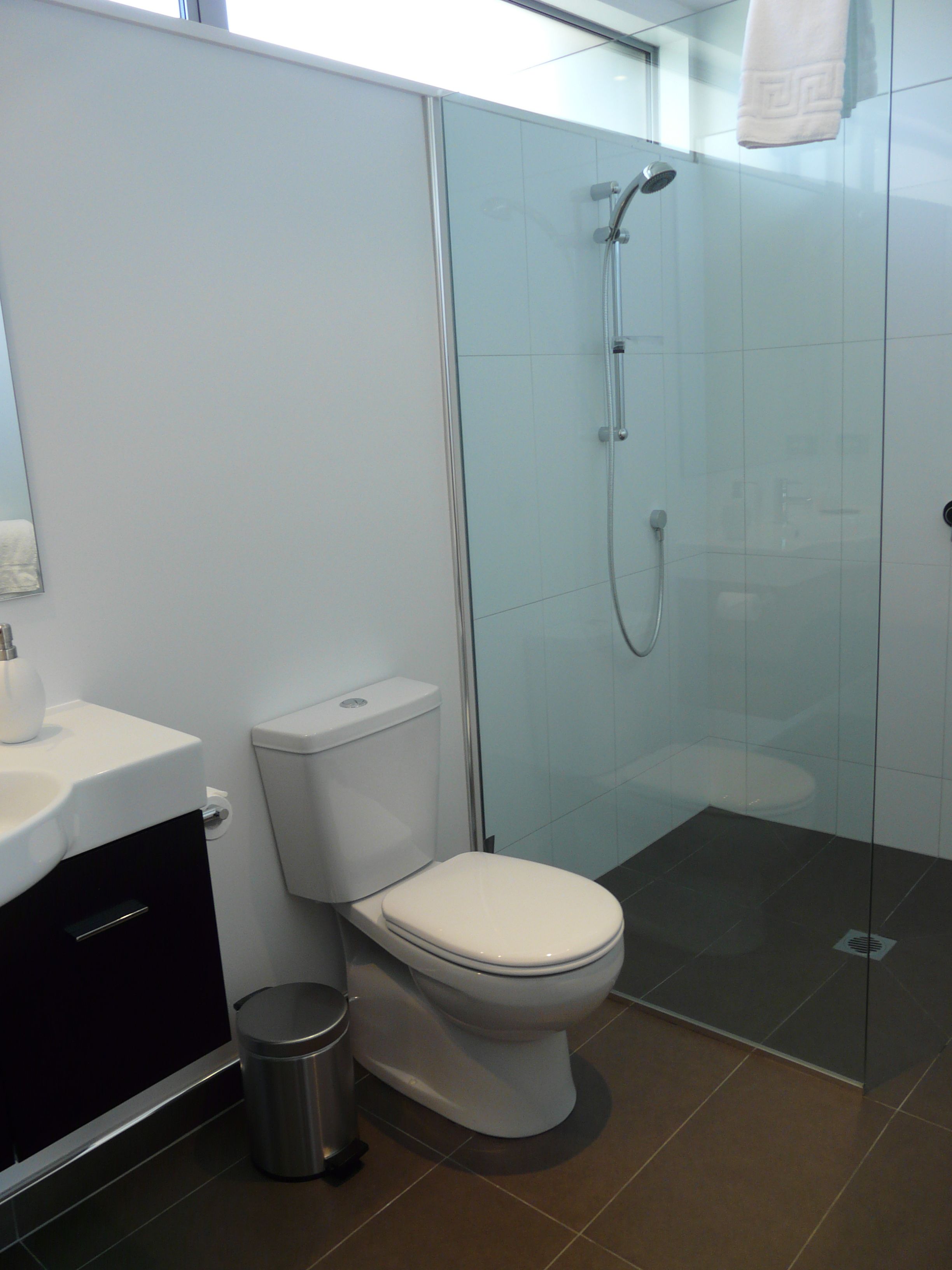 A modern bathroom with a toilet, sink, and shower.