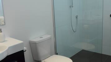 A modern bathroom with a toilet, sink, and shower.