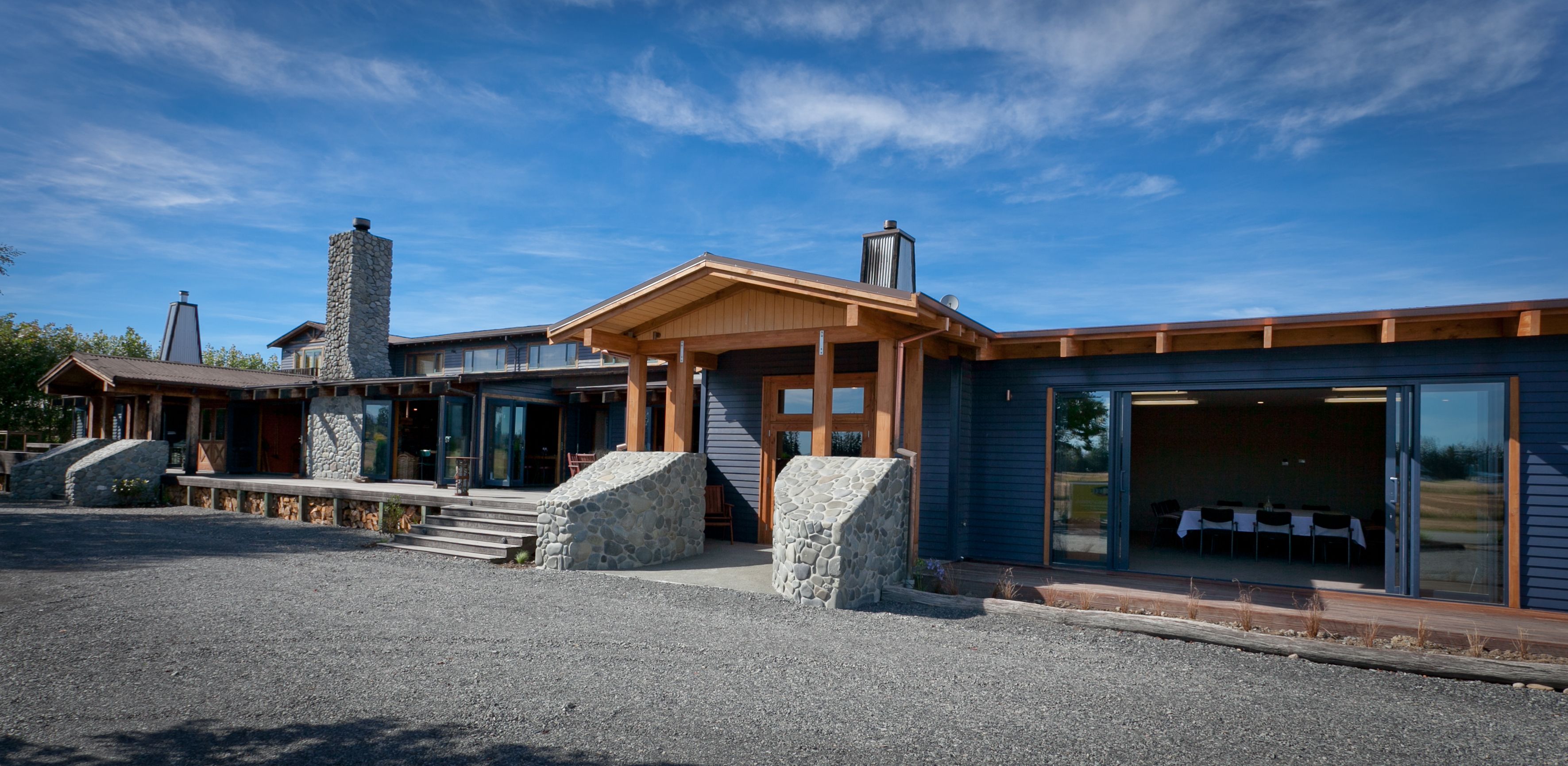 A modern building with a stone facade, wooden beams, and large glass doors.
