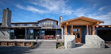 A modern two-story house with a stone chimney, a wooden porch, and a garage.