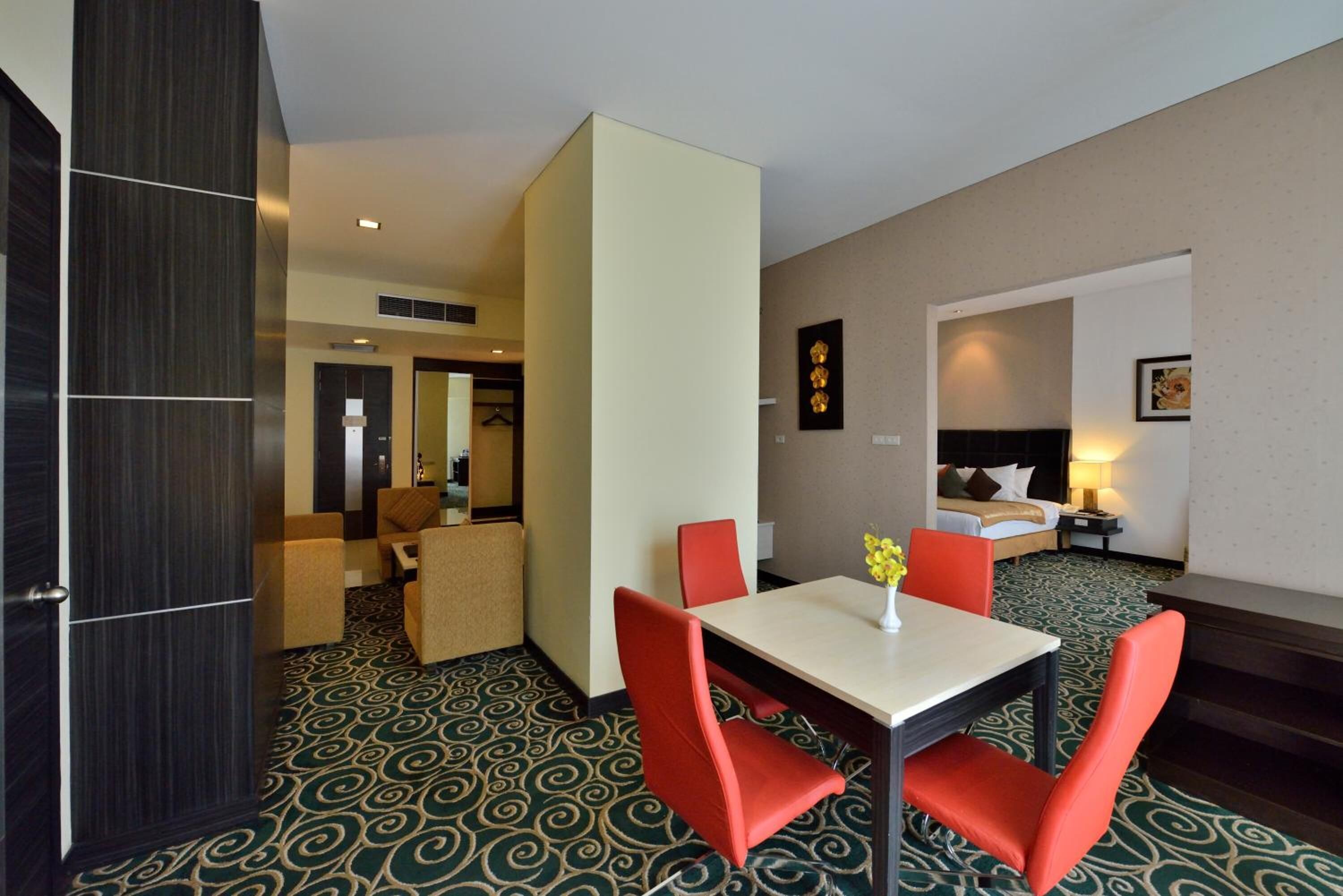 A hotel room with a dining area, a bed, and a bathroom.