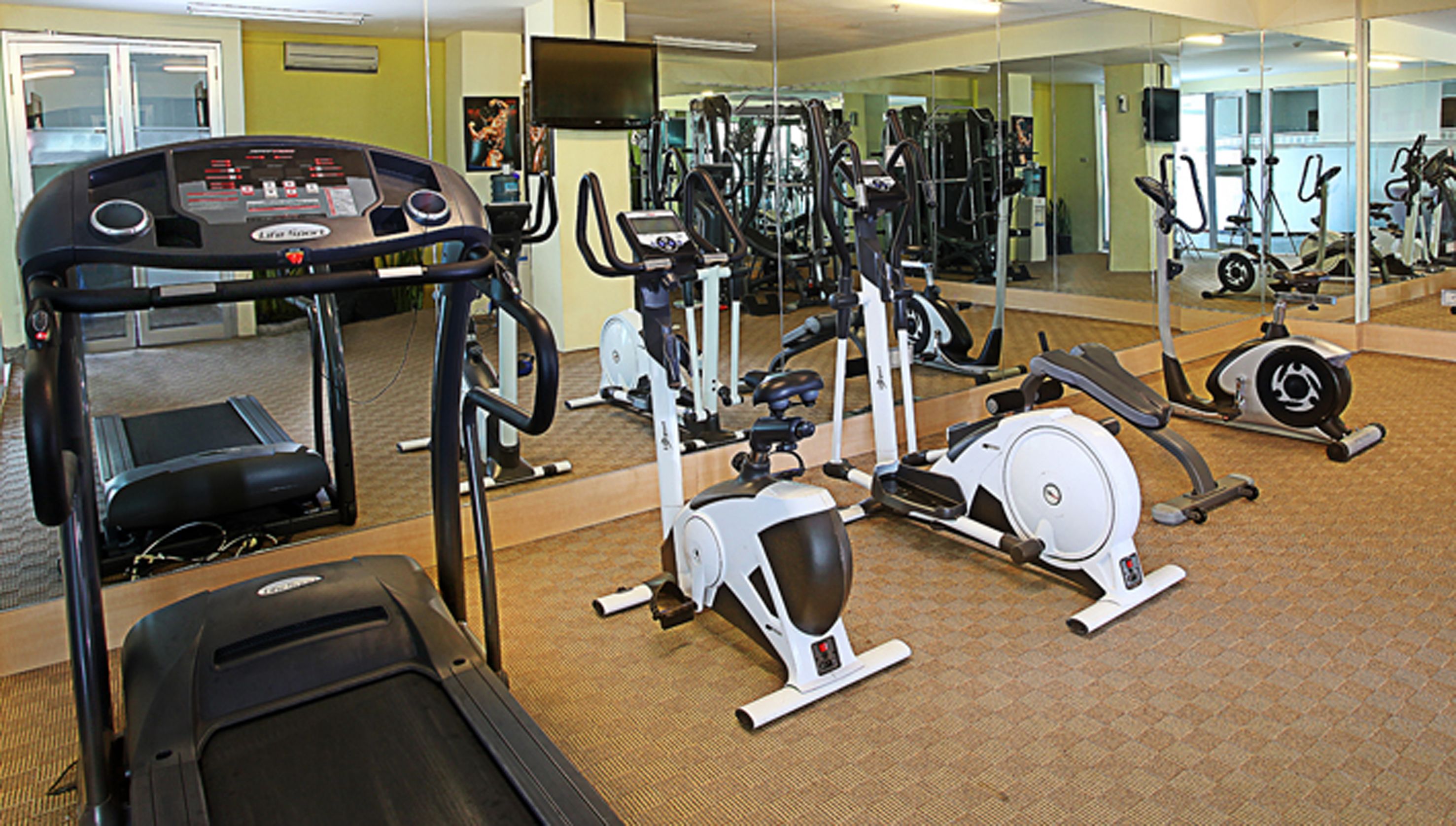 A gym with various exercise equipment including treadmills, elliptical machines, and weight machines.