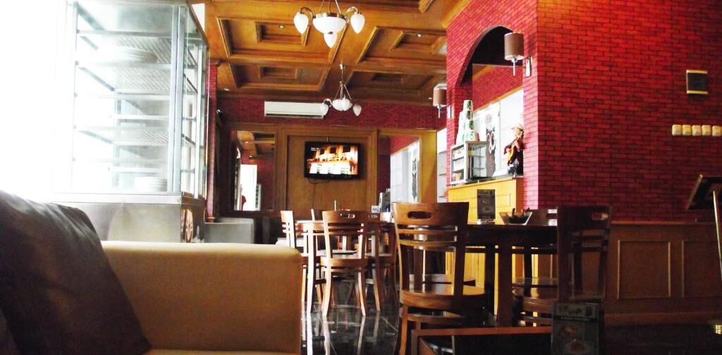 Ein Restaurant mit Holztischen, einem Fernsehbildschirm und Backsteinwänden.