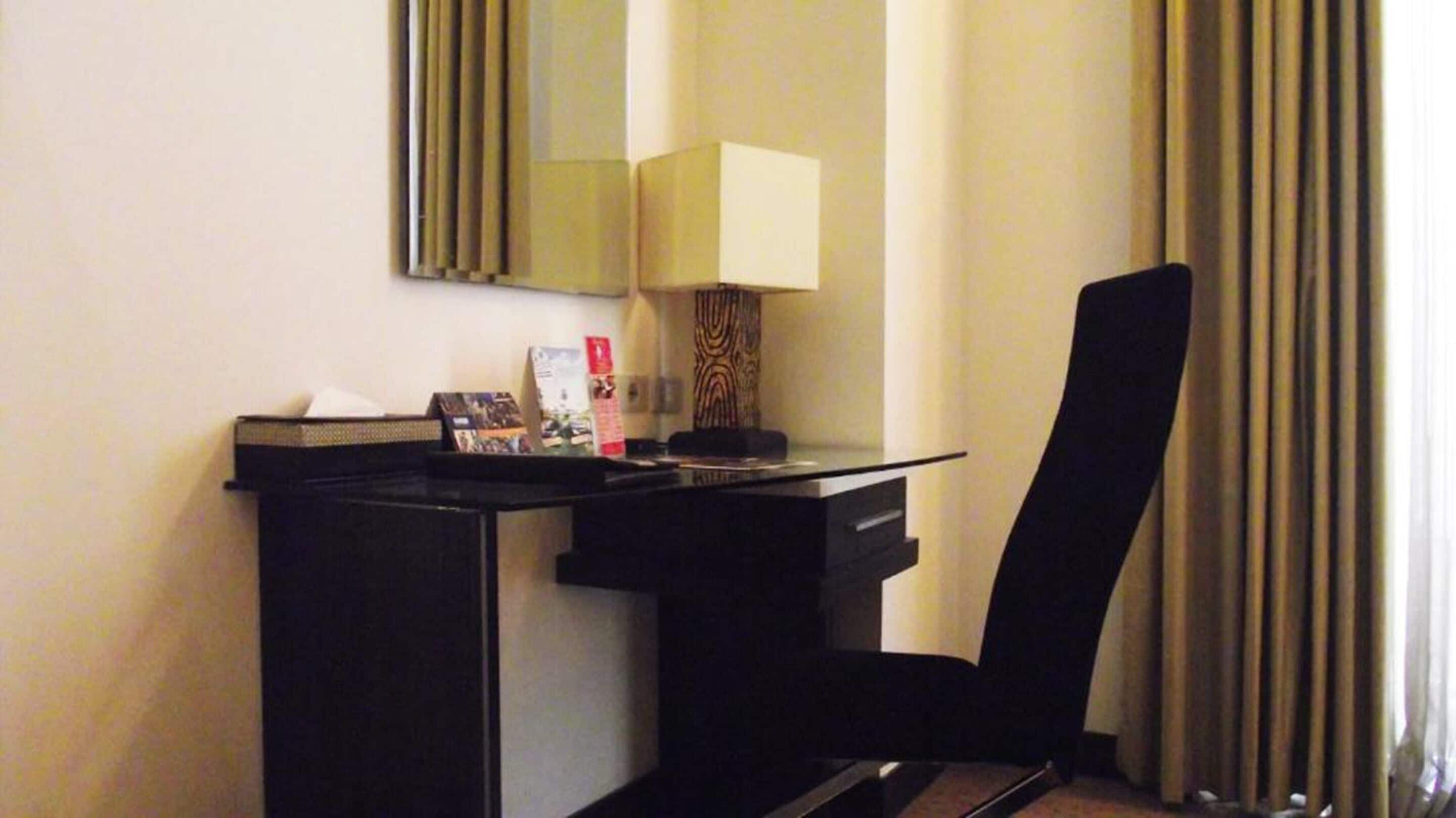 Ein Hotelzimmer mit Schreibtisch, Stuhl, Lampe und Spiegel.