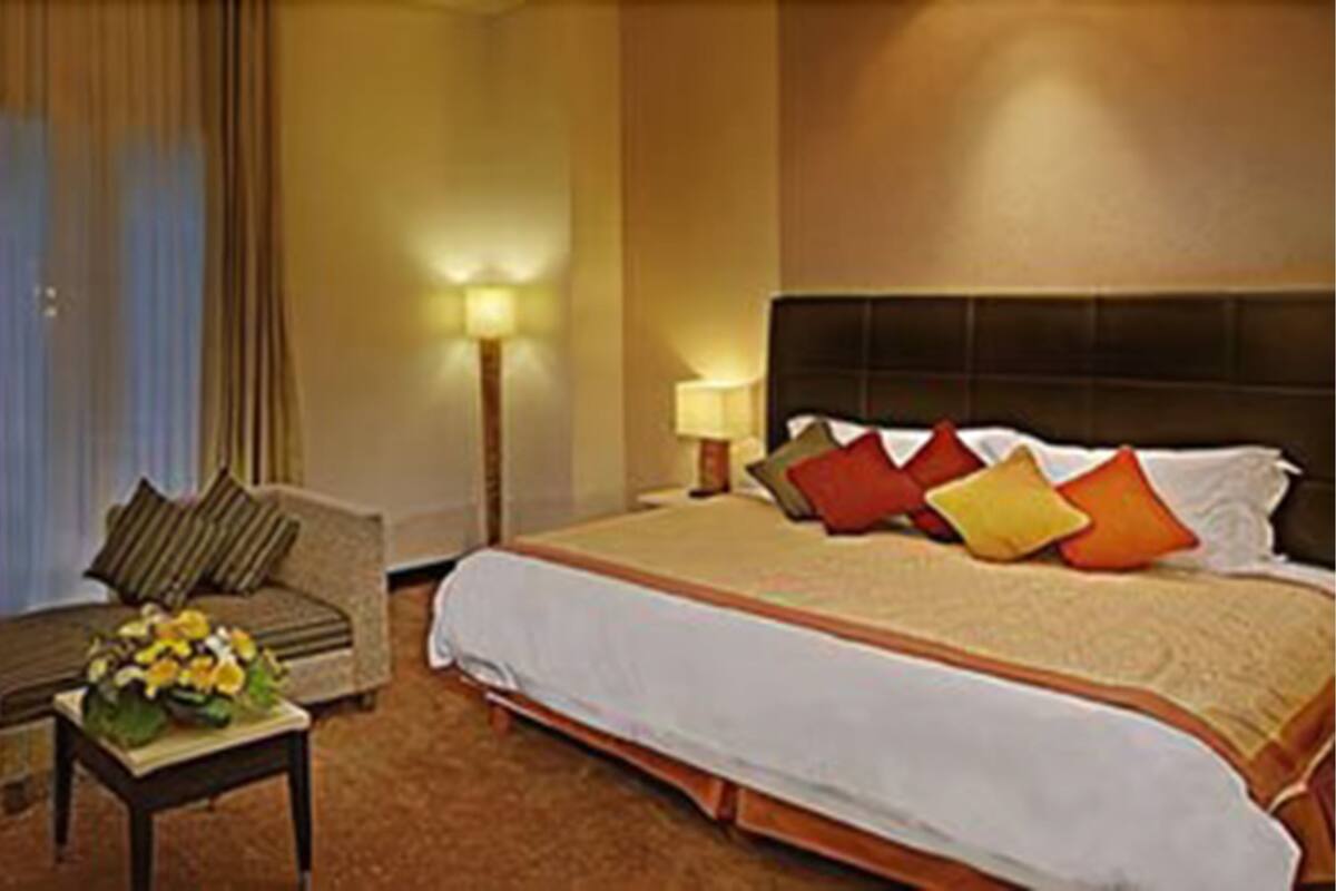 Een hotelkamer met een groot bed, een bank, een nachtkastje en een lamp.