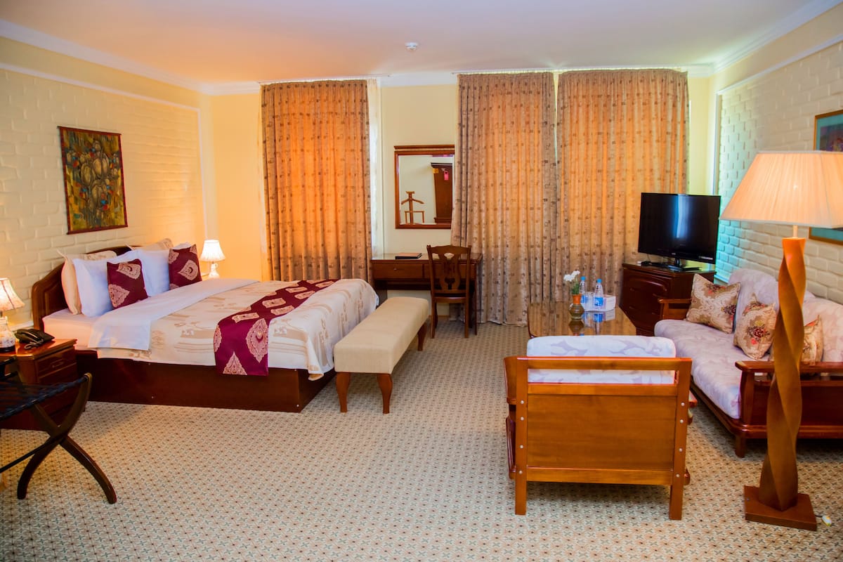 A hotel room with a bed, a desk, a television, a chair, and a sofa.