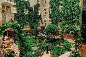 A courtyard with a small pond, potted plants, and wicker furniture.