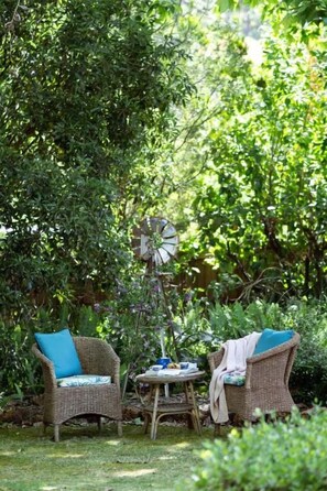 An outdoor seating area with wicker furniture and a windmill. - The Noble Grape Guesthouse (Cowaramup)