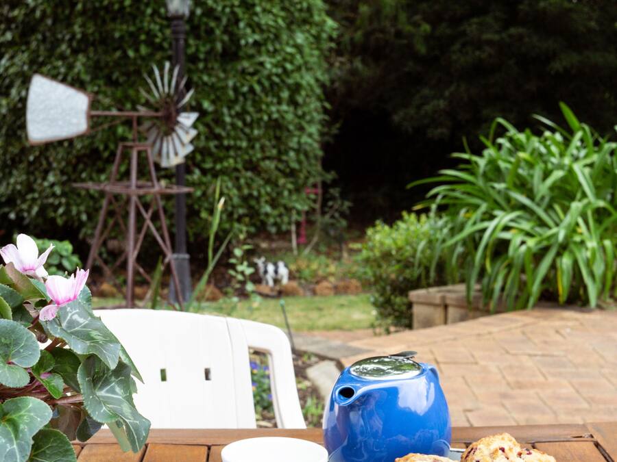 A wooden table with a teapot, cups, and muffins on a tray.