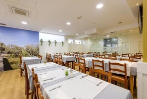 A dining area with tables set for meals, a view of trees through a window, and a modern interior design.