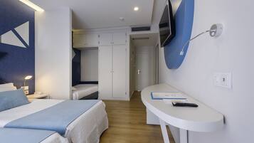 Habitación de hotel con dos camas, un escritorio con silla, televisor montado en la pared y armario.