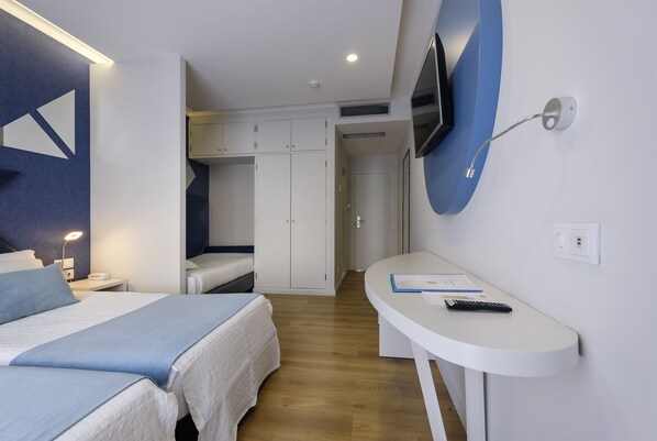 A hotel room with two beds, a desk with a chair, a TV mounted on the wall, and a wardrobe.
