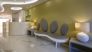 Un espace d’accueil comprenant un banc incurvé, un comptoir de réception et un panneau fixé au mur.