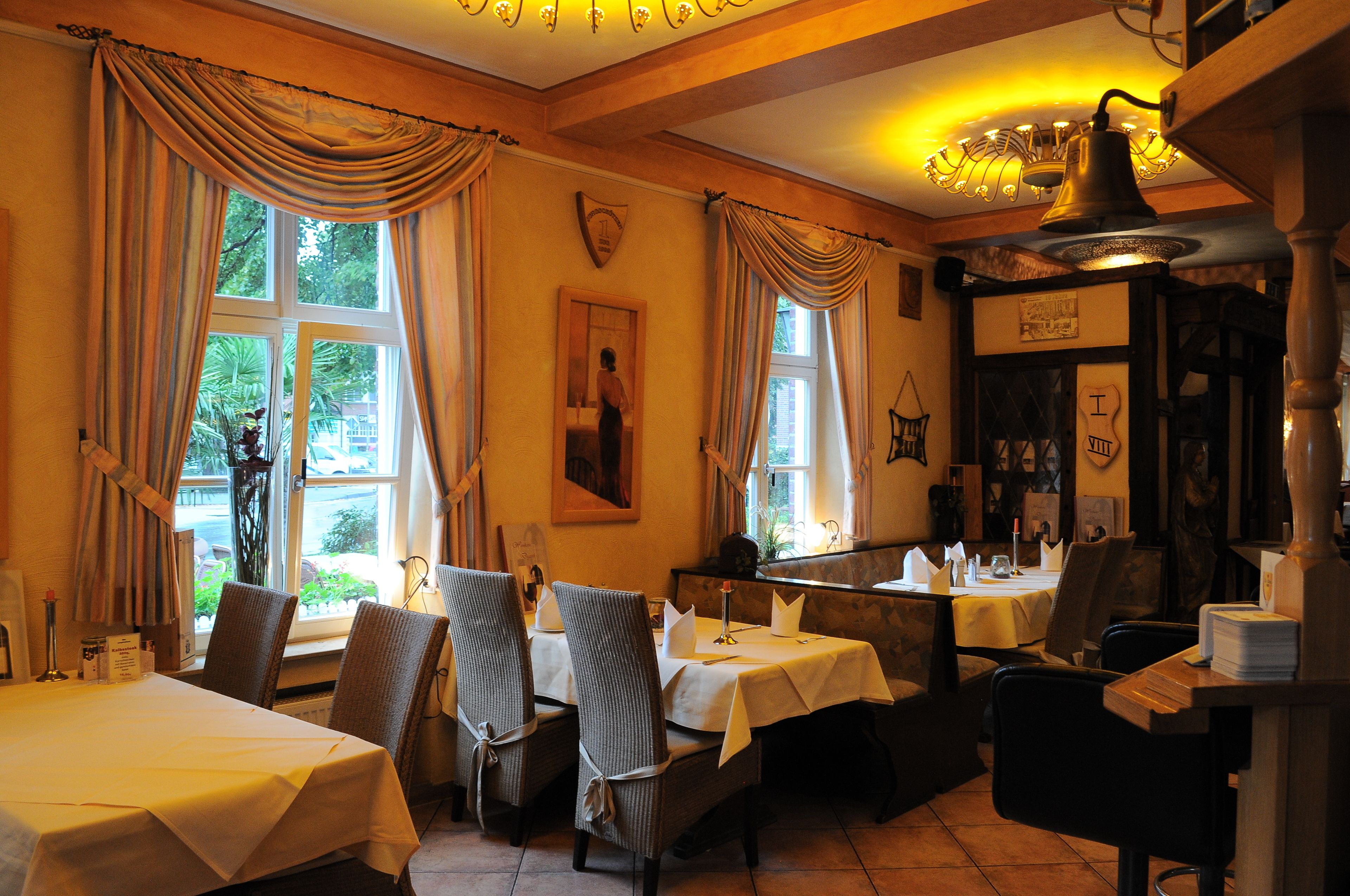 Een restaurant met gedekte tafels, een bel boven de balie en uitzicht op het buitengebied.
