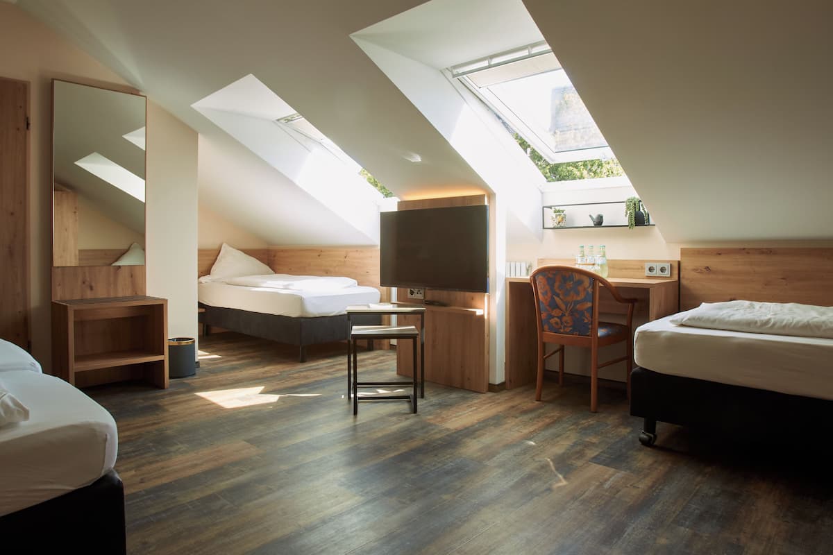 A modern bedroom with a skylight, wooden flooring, a bed, a desk, and a chair.