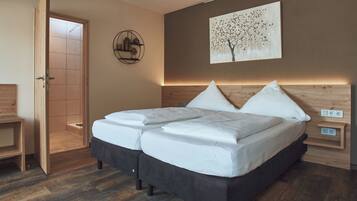 A modern bedroom with a large bed, a wooden headboard, a wall-mounted artwork, and a bedside table with a lamp.