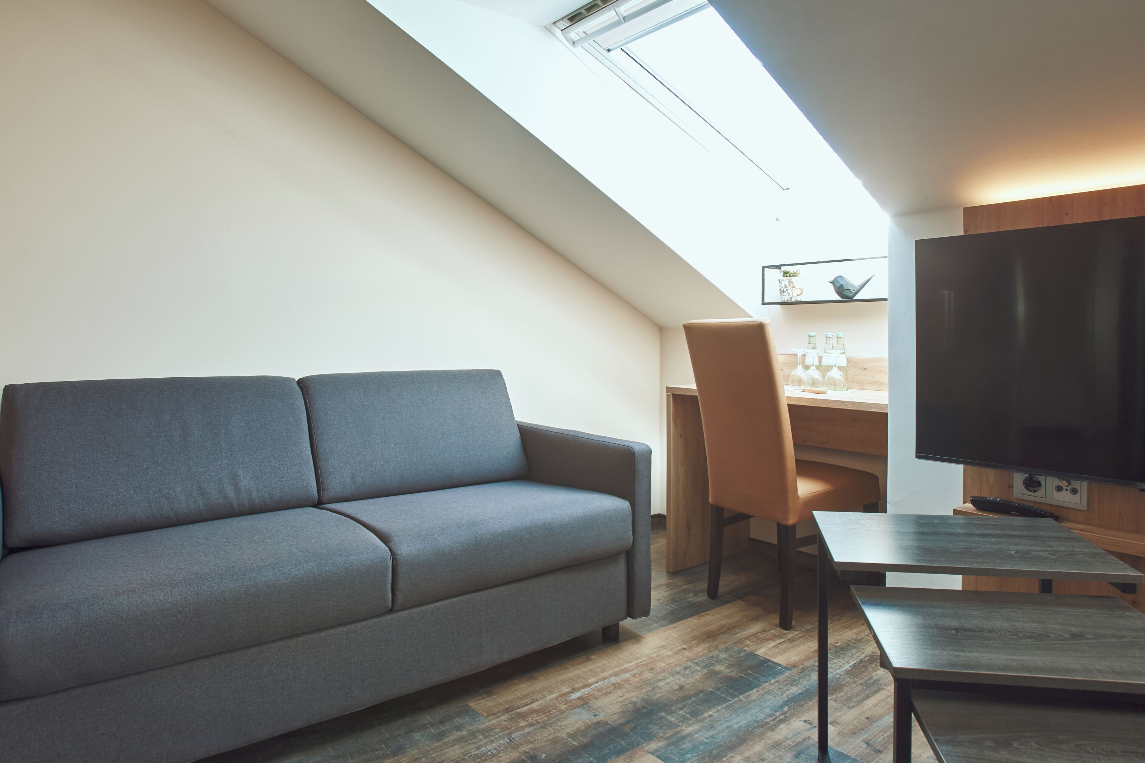 A modern living room with a sofa, a desk, and a flat-screen TV.