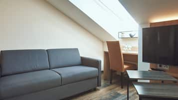 A modern living room with a sofa, a desk, and a flat-screen TV.