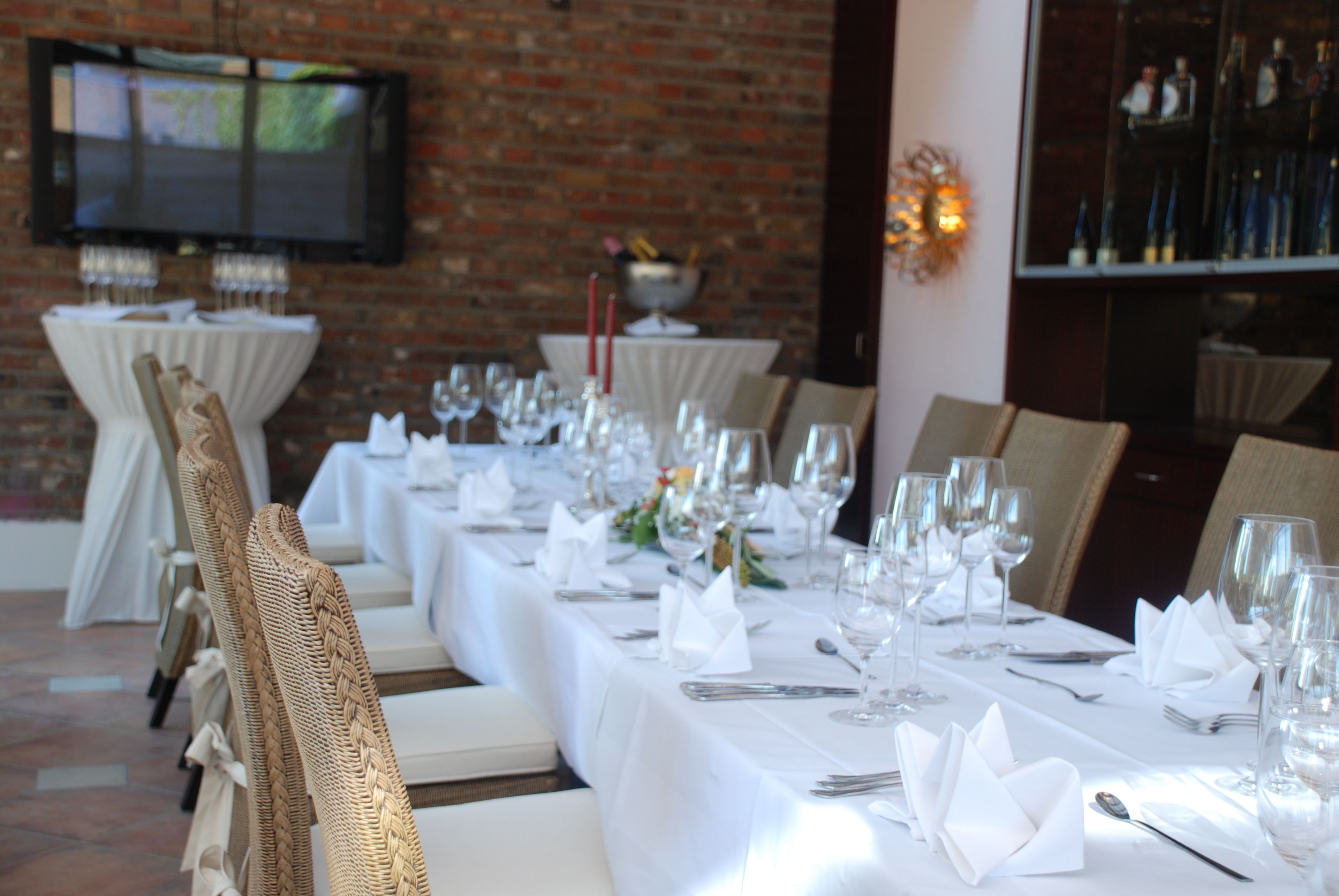 A long dining table set with white tablecloths, glassware, and folded napkins.