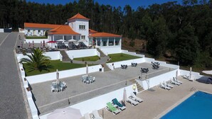 Um resort com piscina, área de estar externa e escadaria que leva a um edifício com telhado vermelho.