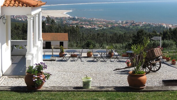 Terraço com vista para o mar, plantas em vasos e um carrinho.