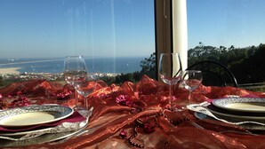Uma mesa posta para dois, com vista para o mar e uma cidade ao fundo.