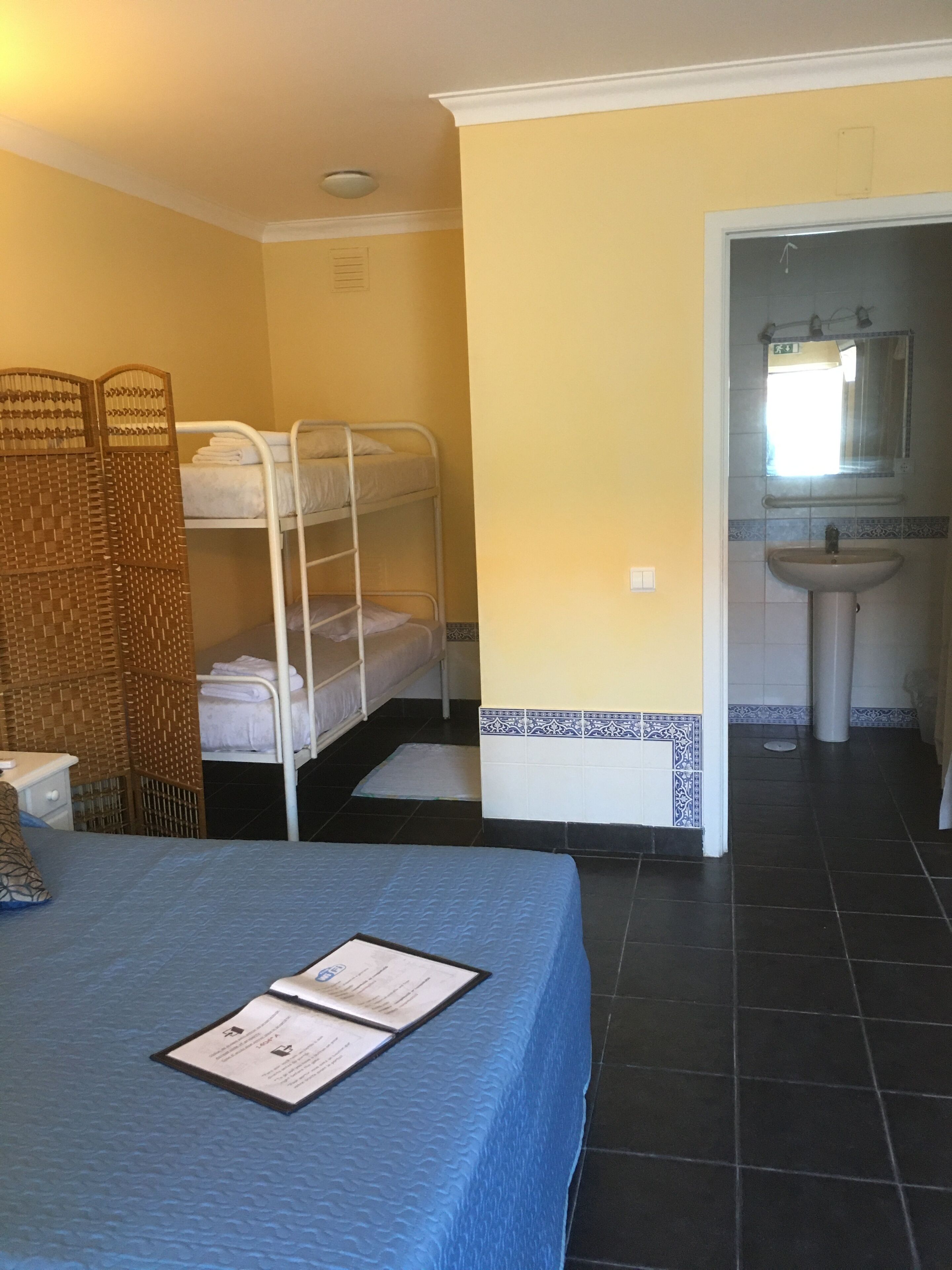 Quarto com beliches, pia e tapete no chão.