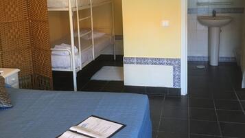Quarto com beliches, pia e tapete no chão.