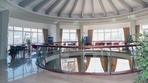 Een ruime atrium met glazen vloer, grote ramen en een centrale trap.