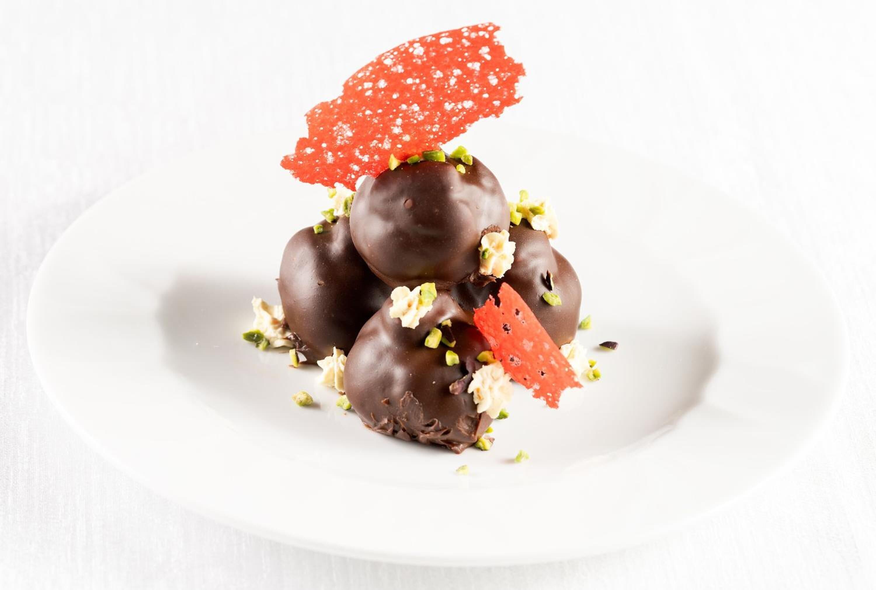 A white plate with chocolate-covered treats and a red decorative piece.