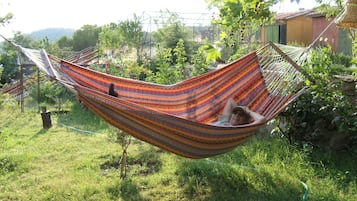 Relax in a hammock suspended between trees in a serene garden setting.