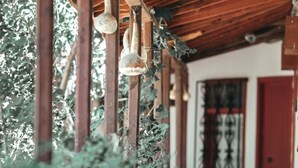 A covered walkway with hanging light fixtures and potted plants. - Assos Terrace Hotel (Ayvacik)