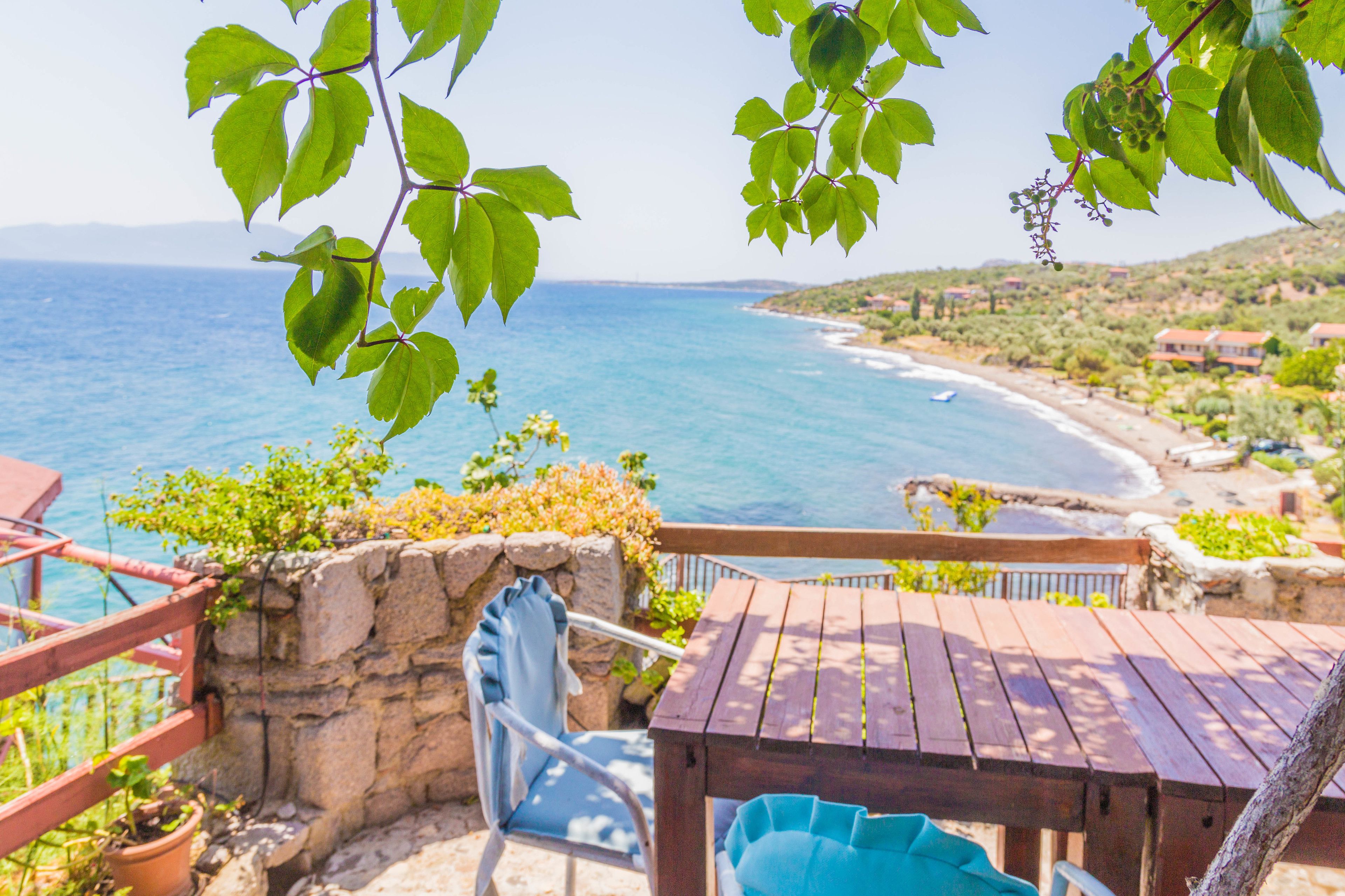Eine Terrasse mit Meerblick, einem Holztisch und einem Stuhl.