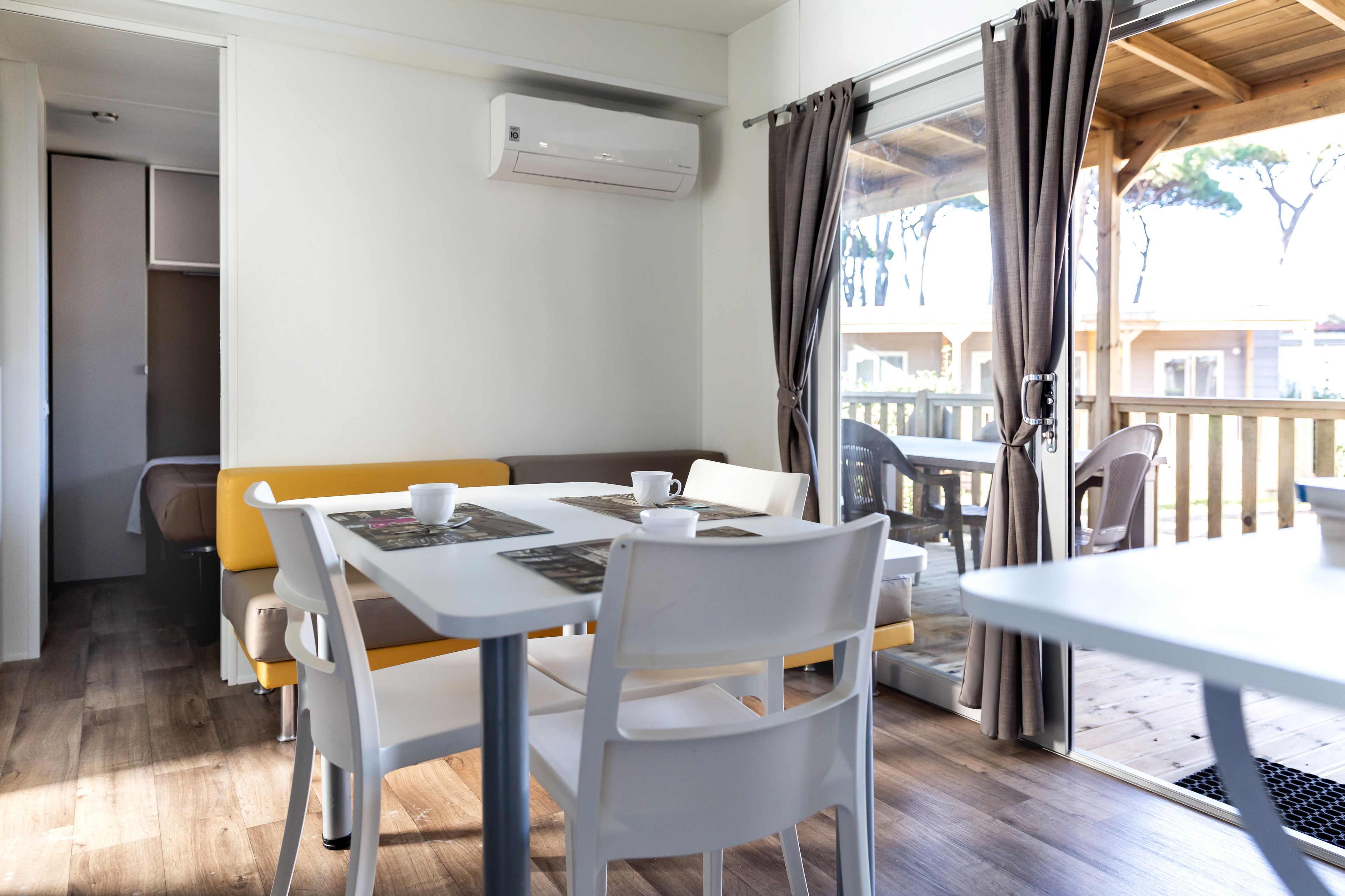 A room with a dining table, chairs, a sofa, and a sliding glass door leading to an outdoor area.