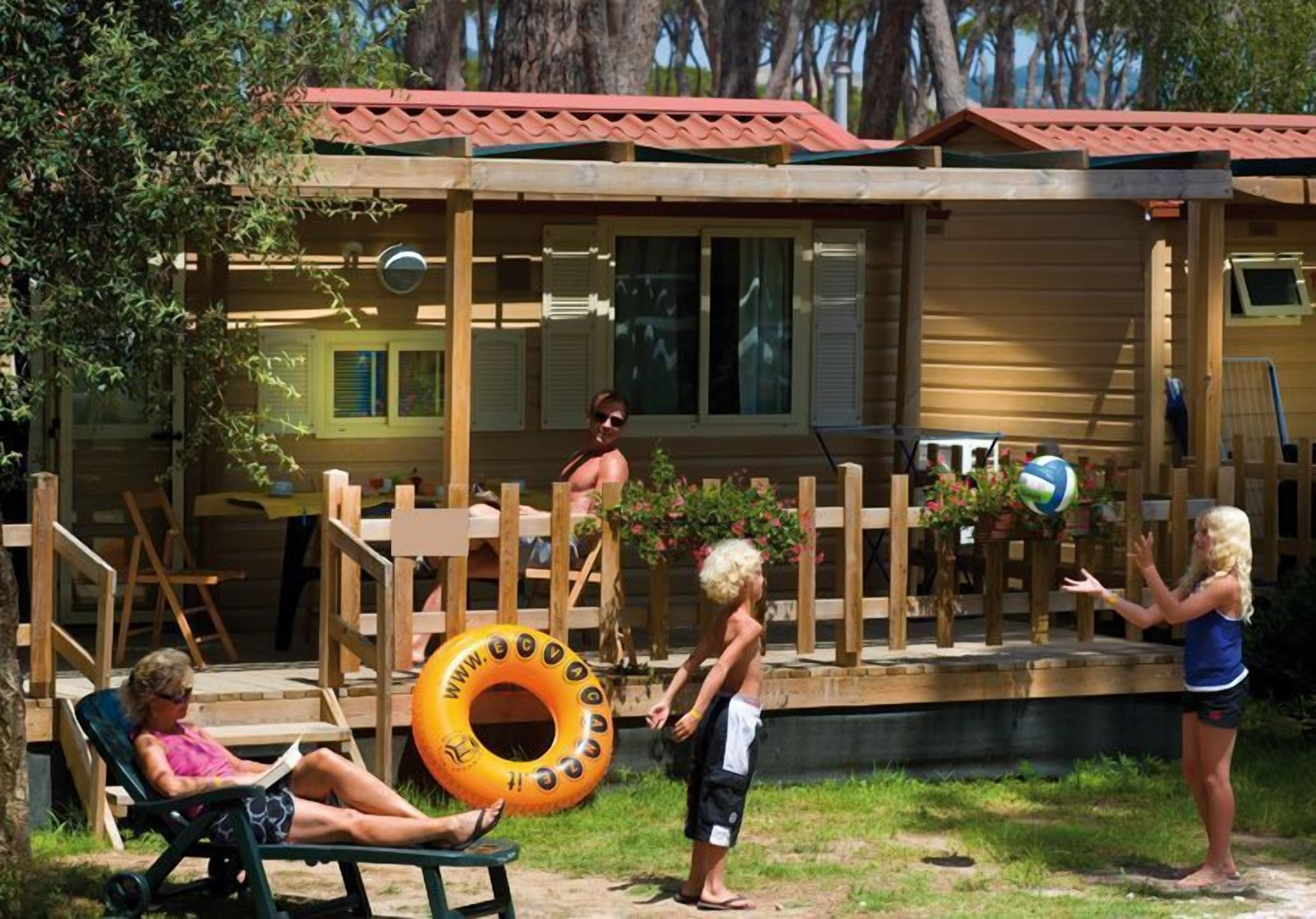 Una baita di legno con tetto rosso, una veranda e una zona piscina.
