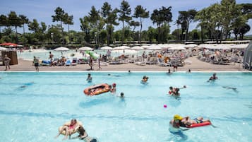 Una piscina techada, sombrillas, sillones reclinables de piscina